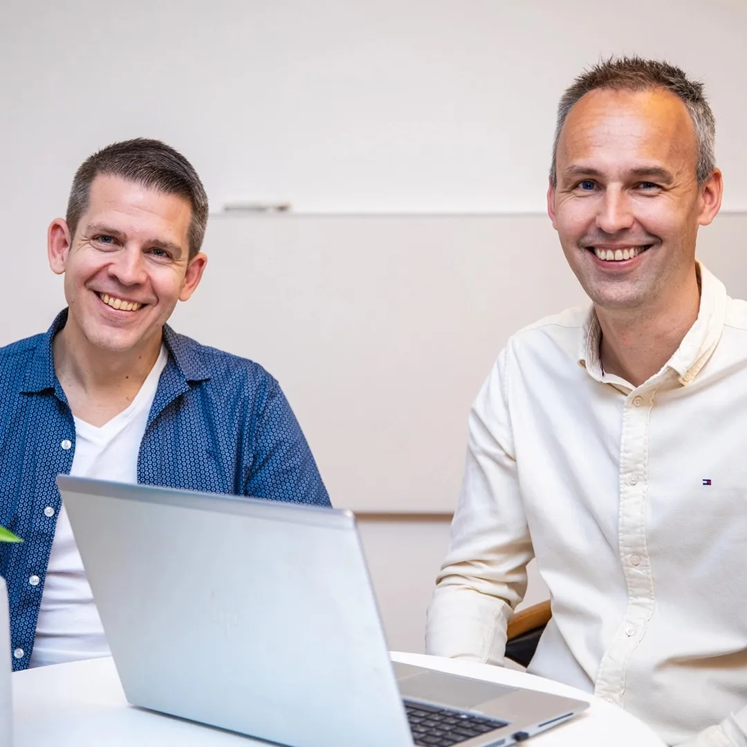 A colleague smiling behind a laptop